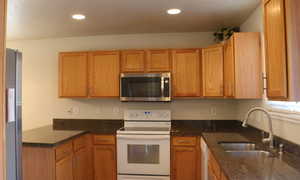 Kitchen featuring a sink, dark stone countertops, stainless steel appliances, and recessed lighting