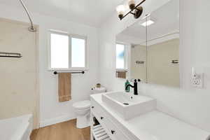 Full bath with wood finished floors, vanity, and bathtub/shower combination