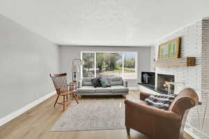 Living room with a view featuring a wood burning brick fireplace.