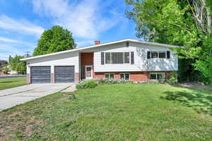 View of front of home featuring an attached garage, a front lawn, brick siding, and spacious driveway