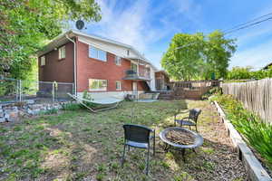 Rear view of house with brick, a fire pit, and a fenced backyard