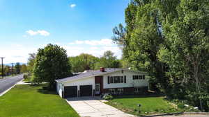 View of front of house with an attached garage and front and side lawn