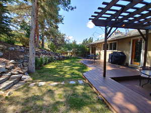 View of yard featuring a pergola, fence, and a wooden deck