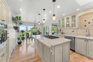 Kitchen featuring cream cabinets, appliances with stainless steel finishes, a sink, backsplash, and a skylight
