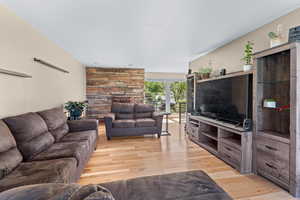 Living room with light wood-type flooring and a stone fireplace