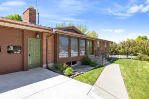View of exterior entry featuring a yard, brick siding, and a chimney