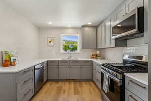 Kitchen featuring new gray cabinets, new backsplash & quartz countertops, new light wood vinyl flooring, new stainless steel appliances, and recessed lighting
