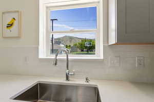 Interior kitchen details featuring light quartz countertops, with a mountain view from the kitchen sink