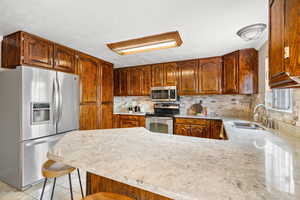 Kitchen with a granite countertop, tile floors,  appliances with stainless steel finishes, and tile backsplash
