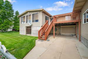 Rear view of property with a lawn, a deck, a sunroom, and stairway