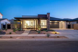 Contemporary home with fence, covered porch, an attached garage, and concrete driveway