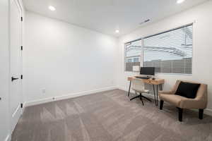 Carpeted office space featuring baseboards, recessed lighting, and visible vents
