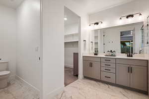 Full bath with toilet, baseboards, a sink, and marble finish floor