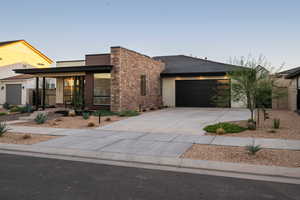 Contemporary home with a garage, stucco siding, concrete driveway, and stone siding