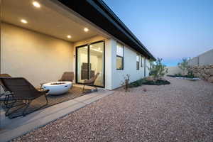 Exterior space featuring a patio area, an outdoor fire pit, stucco siding, and fence private yard