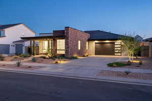 Contemporary home featuring a garage, stucco siding, driveway, and stone siding