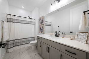 Bathroom featuring toilet, curtained shower, marble finish floor, and vanity