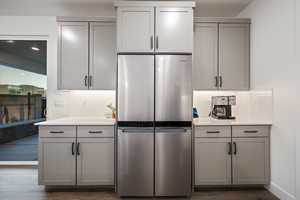 Kitchen featuring freestanding refrigerator, dark wood finished floors, backsplash, and gray cabinetry