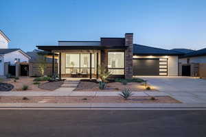 Modern home featuring fence, a garage, a gate, covered porch, and driveway