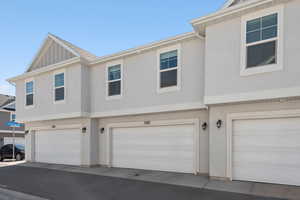 View of rear facade with board and batten siding, an attached garage, and stucco siding