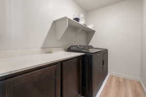 Laundry room with baseboards, cabinet space, and light wood-style floors