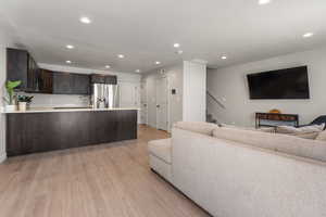 Living area with stairway, baseboards, recessed lighting, and light wood-style flooring
