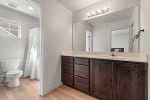 Primary full bathroom with wood finished floors, toilet, and vanity