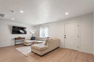Living room featuring light wood-style floors, baseboards and recessed lighting