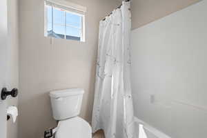 Full bath with a shower with curtain and toilet