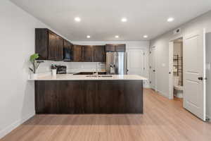Kitchen with range with electric stovetop,  black microwave, and a sink