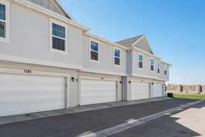 View of rear of home featuring board and batten siding, an attached garage, and stucco siding