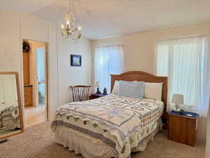 Primary Bedroom with carpet, vaulted ceiling, a textured ceiling, and a notable chandelier