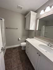 Full bath with vanity, toilet, a textured ceiling, baseboards, and visible vents