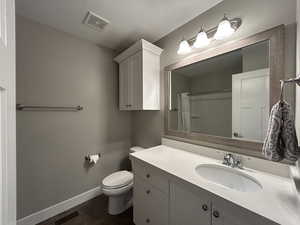 Full bath with baseboards, vanity, toilet, and visible vents