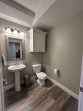 Bathroom with baseboards, a textured ceiling, wood finished floors, and toilet