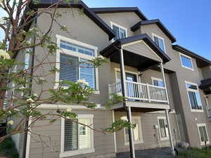 Back of property featuring a balcony and stucco siding