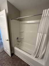 Bathroom with tile patterned floors, shower / bathtub combination with curtain, and a textured ceiling
