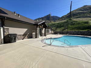 Community pool with a patio area, a mountain view, and fence