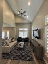 Living room with high vaulted ceiling, a ceiling fan, baseboards, recessed lighting, and wood finished floors