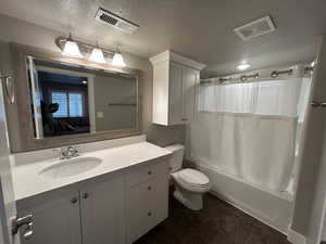 Full bath with visible vents, shower / bath combo with shower curtain, toilet, and vanity