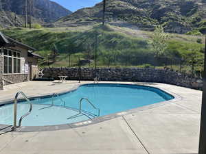 Community pool with fence, a mountain view, and a patio area