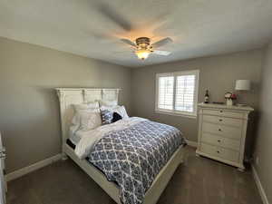 Bedroom with baseboards, ceiling fan, and dark colored carpet