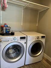 Main floor clothes washing area featuring separate washer and dryer, baseboards, laundry area, and wood finished floors