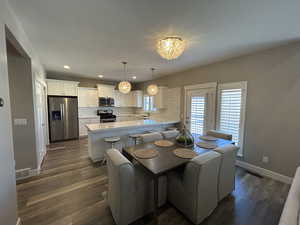 Dining area with visible vents, dark wood-style flooring, baseboards, recessed lighting, and a notable chandelier