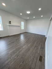 Unfurnished living room featuring recessed lighting, visible vents, baseboards, and dark wood-style floors