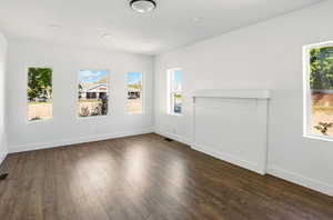Unfurnished living room with baseboards, visible vents, and dark wood-style floors