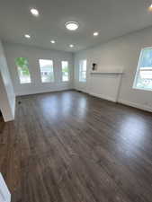 Unfurnished living room featuring dark wood-style floors and a healthy amount of sunlight
