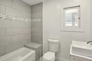 Full bath featuring toilet, baseboards, and a sink