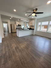 Kitchen featuring dark countertops, stainless steel appliances, white cabinets, and dark wood-type flooring