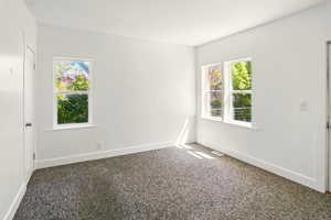 Empty room featuring a healthy amount of sunlight, baseboards, and carpet flooring